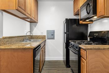 a kitchen with black appliances and granite counter tops at Riverside Villas Apartments, California, 91602